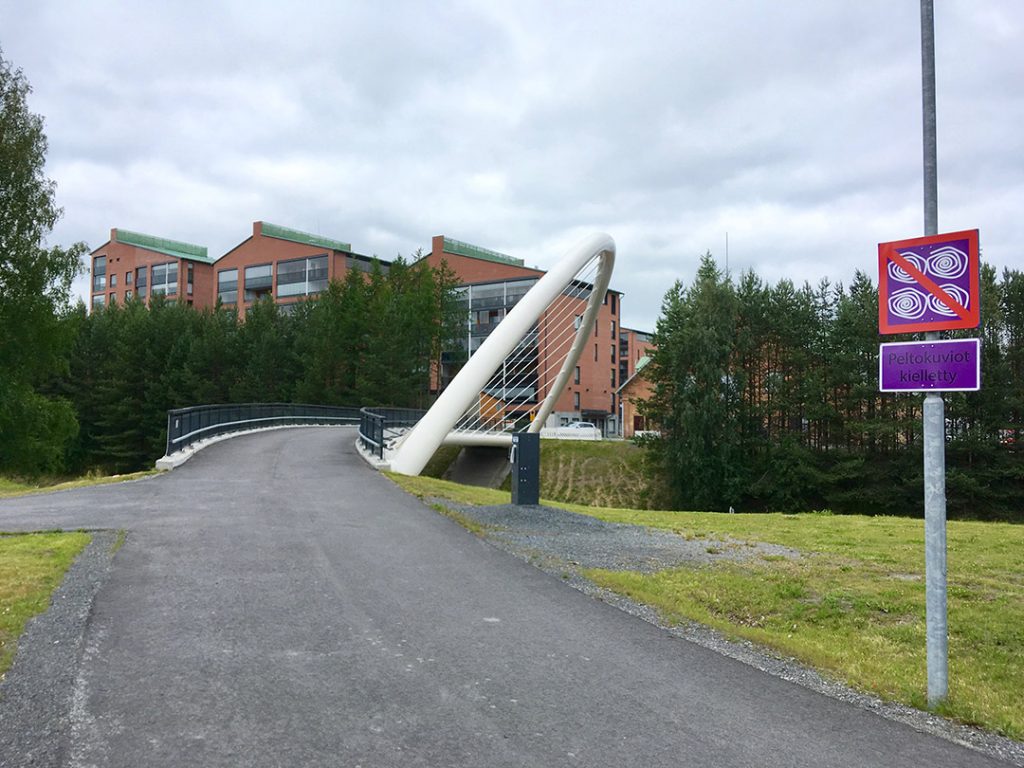 An art traffic sign in front a bridge and apartment buildings