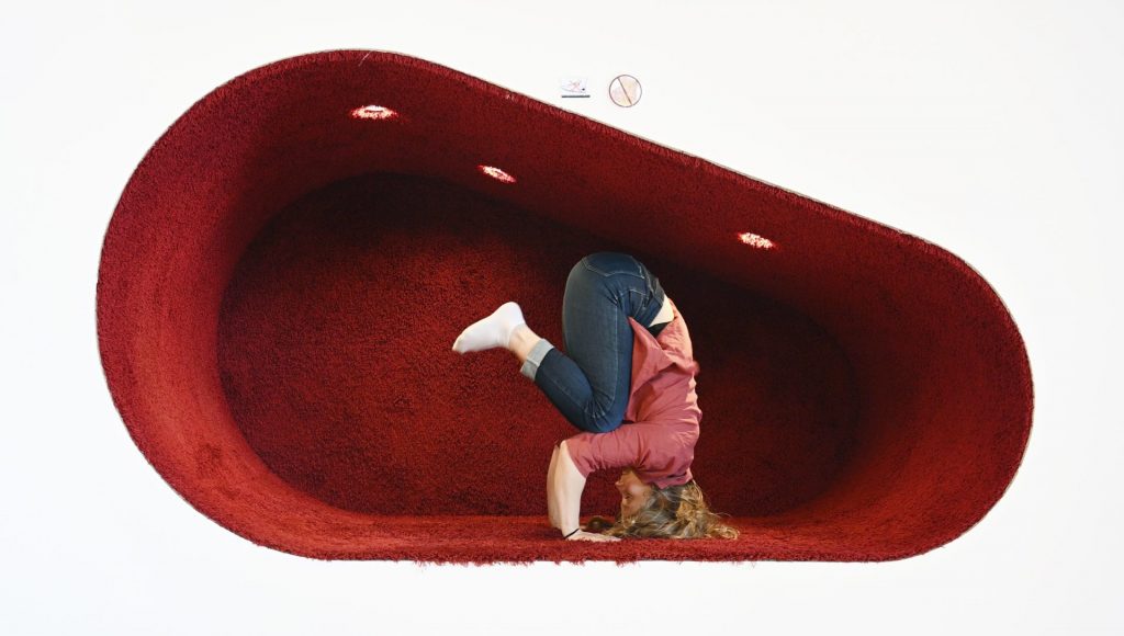 Woman up side down in a Yoga pose in a reading corner at the local library in Seinäjoki