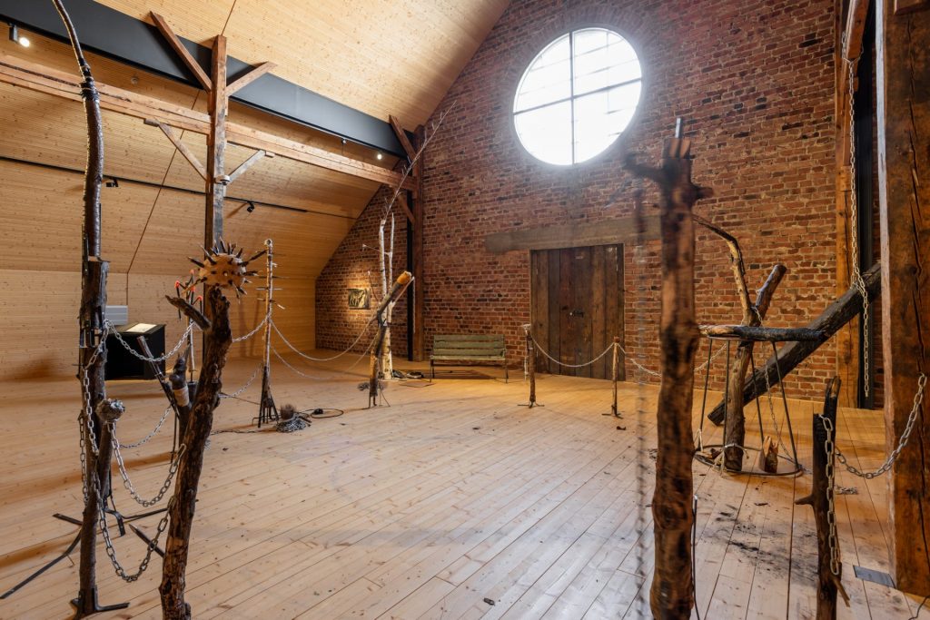 exhibition space that has sculture installation with wooden object in a circle