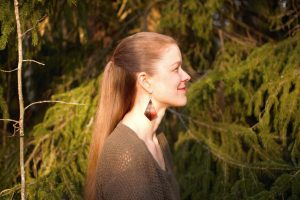 nainen metsässä, sivuprofiili ja aurinkopaistaa kasvoille