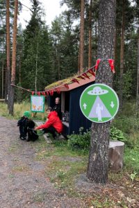 Lentävää lautasta esittävä liikennemerkki kuntopolun varrella metsässä