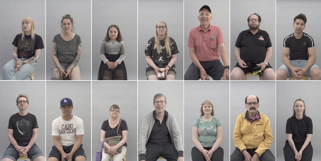 ihmiset katsovat istuen kameraan päin