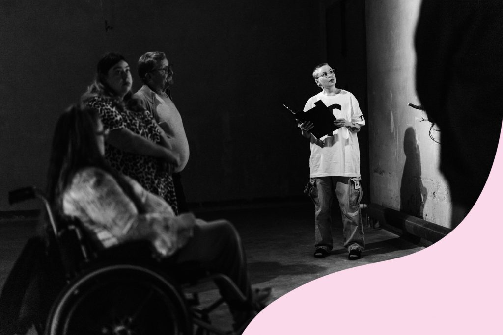 People gathered around a guide to listen to a guided tour of an art exhibition.