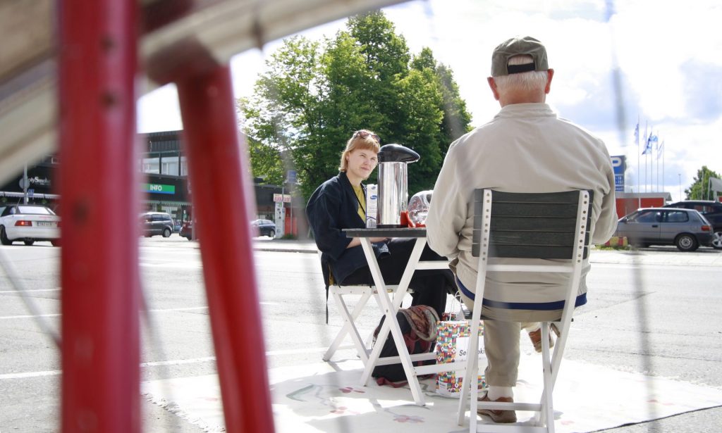 A woman and an older man sitting and drinking coffee.