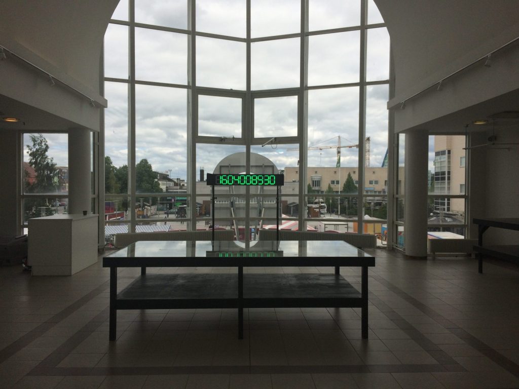 ostoskeskuksen ikkuna jossa keskellä videoteos missä numeroita